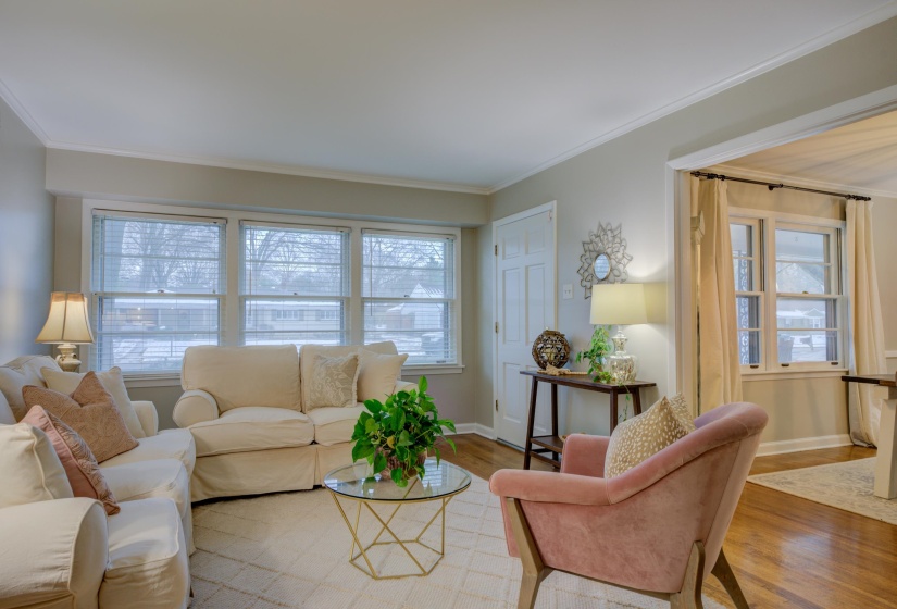 Bright living space featuring multiple large windows, crown molding, a built-in door, an arched doorway, and wood-finish flooring