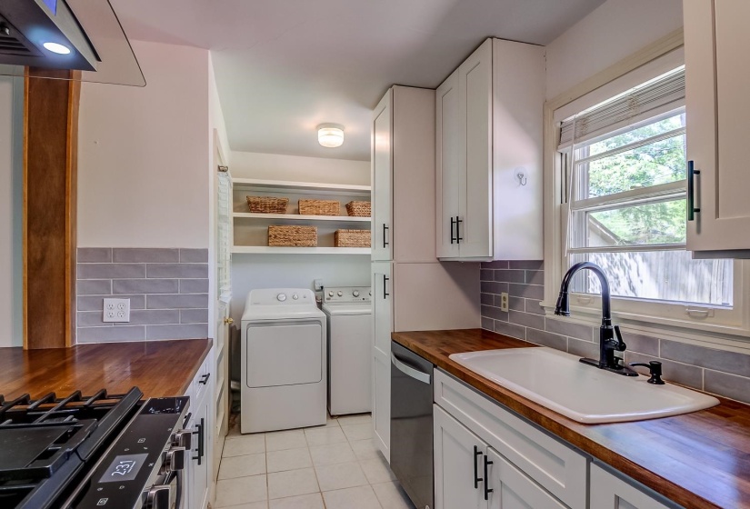 Kitchen with wood counters, stainless steel appliances, washer and dryer, and white cabinets
