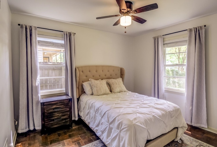 Bedroom featuring dark wood-type flooring, multiple windows, and a ceiling fan