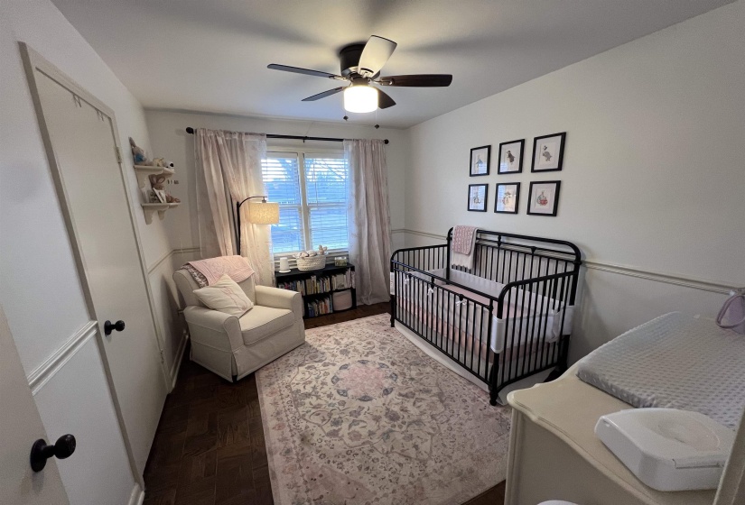 Bedroom with a nursery area, parquet flooring, and ceiling fan