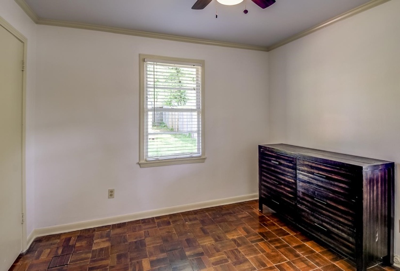 Unfurnished bedroom with crown molding, parquet floors, and a ceiling fan