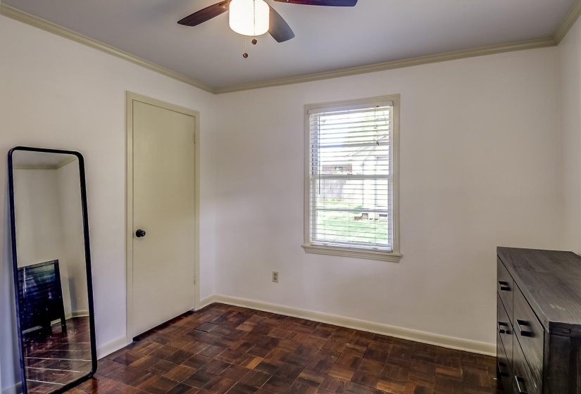 Unfurnished bedroom with parquet floors, ornamental molding, and ceiling fan
