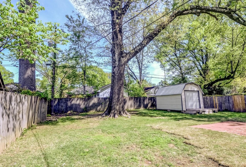 Fenced backyard featuring a storage shed
