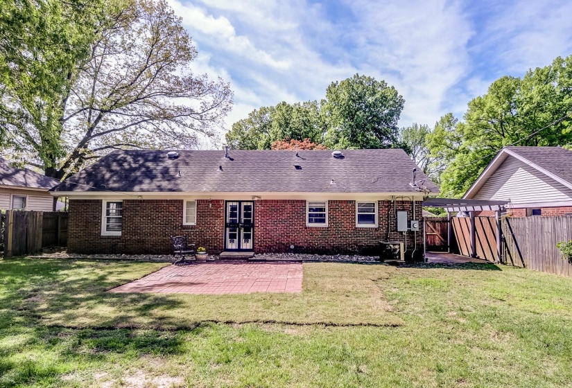 Back of property featuring a patio area, a fenced backyard, a shingled roof, and brick siding