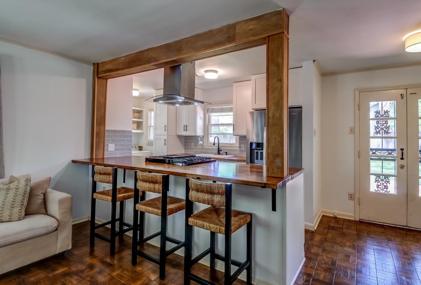 Kitchen featuring decorative backsplash, white cabinets, wooden counters, parquet floors, and island range hood