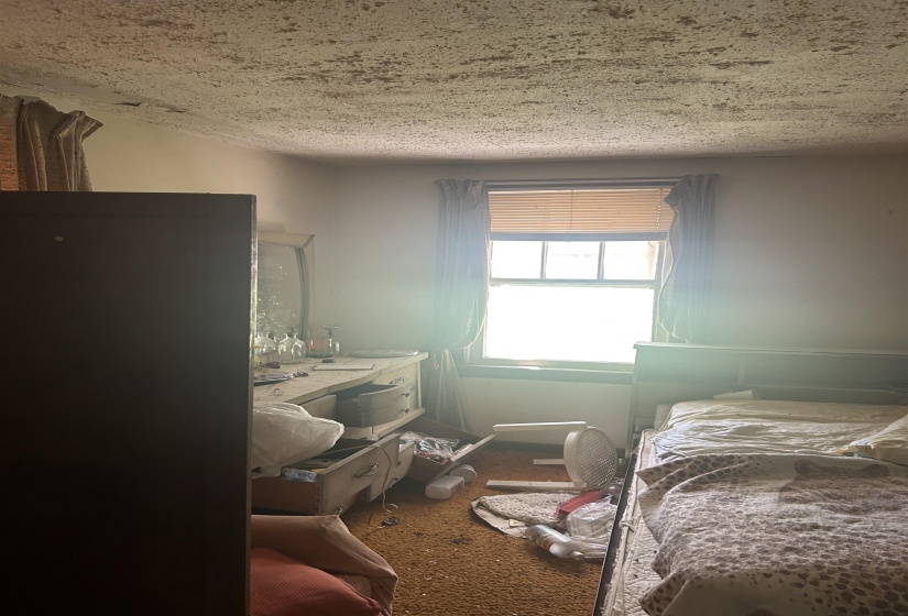Bedroom featuring dark colored carpet and a textured ceiling
