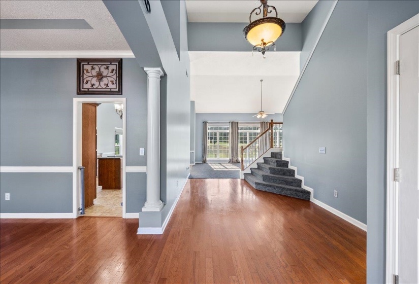 Foyer featuring ornate columns, dark wood-style flooring, a high ceiling, and ceiling fan