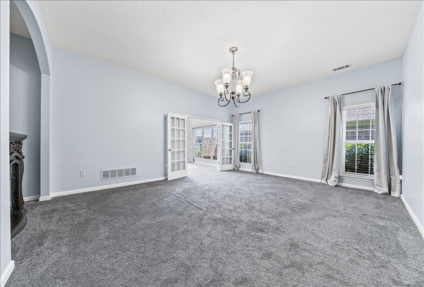 Unfurnished dining area with a textured ceiling, hanging lights, dark colored carpet, and arched walkways