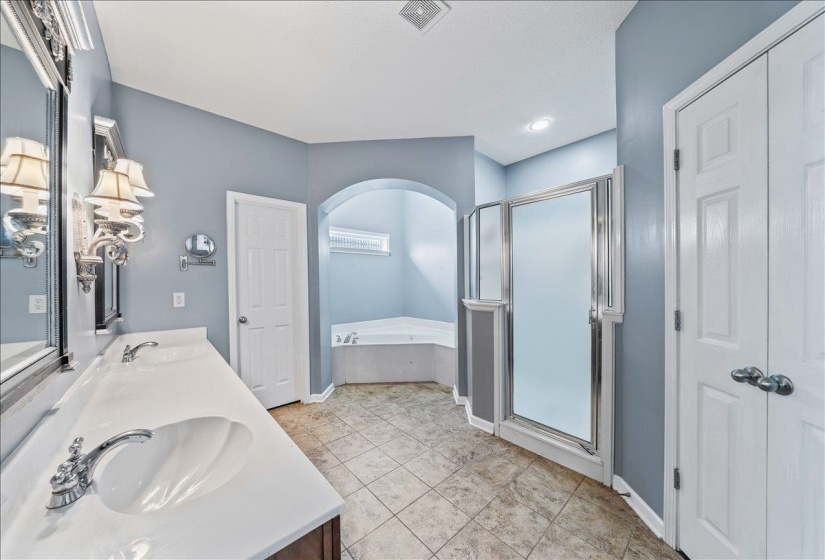 Bathroom with double vanity, a bath, a shower stall, and light tile patterned floors