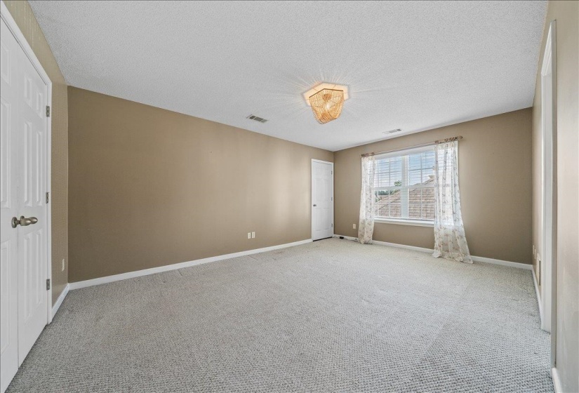 Unfurnished bedroom featuring a closet, a textured ceiling, and light carpet
