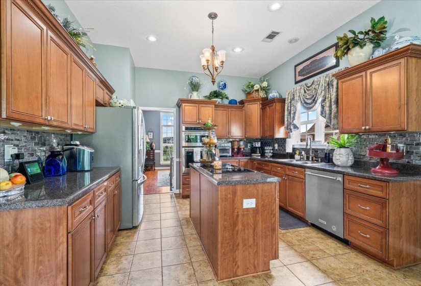 Kitchen featuring wood cabinetry, dark countertops, a central island, stainless steel appliances, and tile flooring