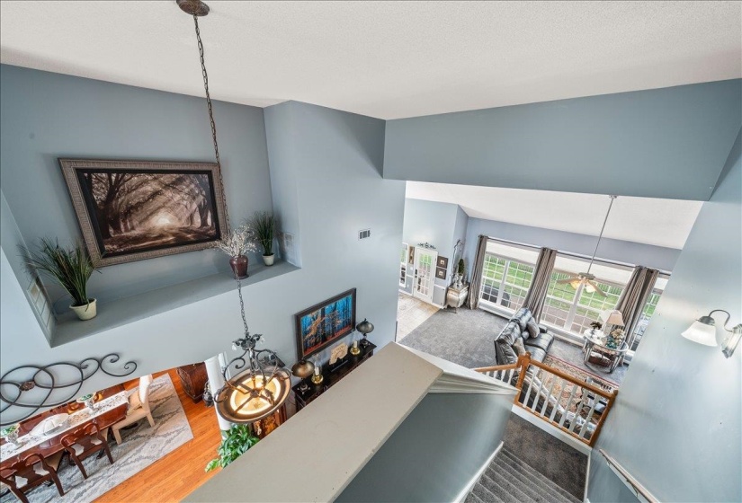 Multi-level interior featuring a carpeted staircase with wood banister, a light blue wall palette, and an open concept layout