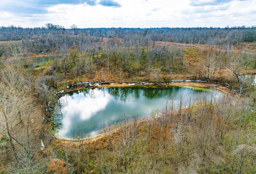 Drone / aerial view of a heavily wooded area and a nearby body of water