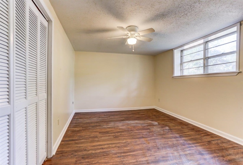 Unfurnished bedroom with a closet, dark wood finished floors, ceiling fan, and a textured ceiling