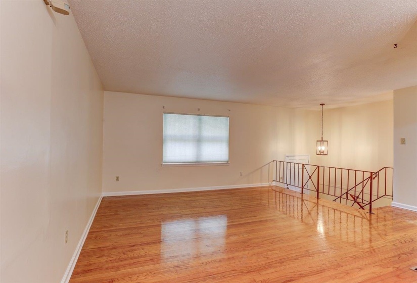 Empty room featuring light wood finished floors, a chandelier, and a textured ceiling