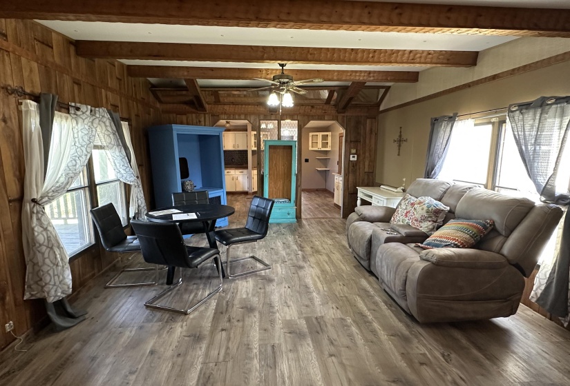 Living area with ceiling fan, wood finished floors, beamed ceiling, wood walls, and arched walkways