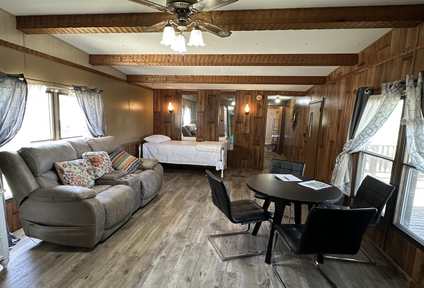 Living room featuring wooden walls, wood finished floors, and beamed ceiling