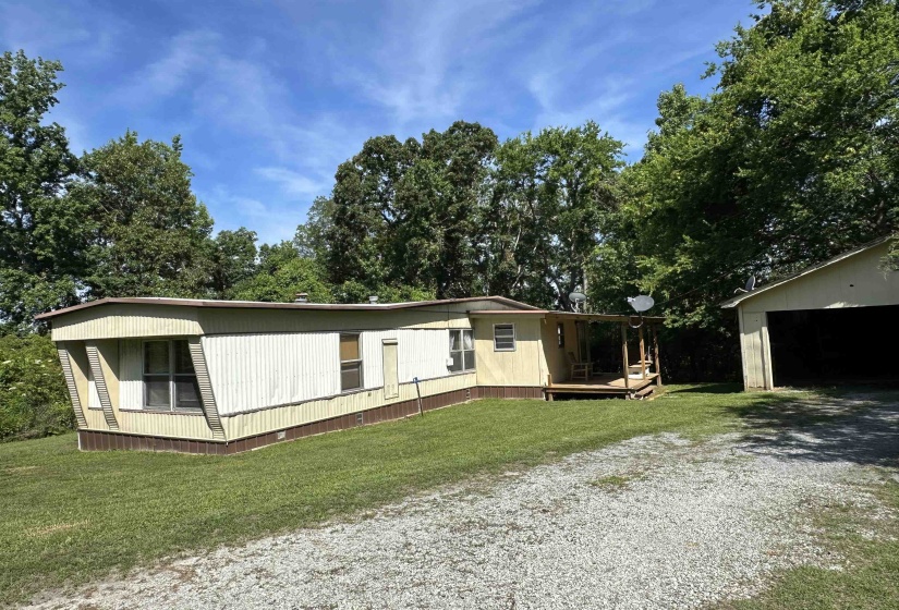 Single-story residence featuring a covered porch, gravel driveway, and a detached two-car garage