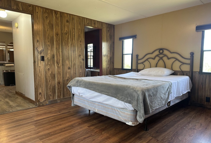 Bedroom with wooden walls, dark wood-style flooring, and multiple windows
