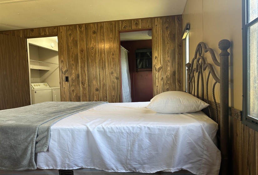 Bedroom with wooden walls, separate washer and dryer, and multiple windows