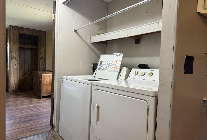 Laundry area featuring dark wood-style floors, washer and clothes dryer, and wood walls
