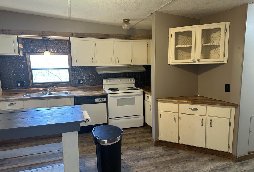 Kitchen featuring white appliances, dark wood-style floors, backsplash, and white cabinets