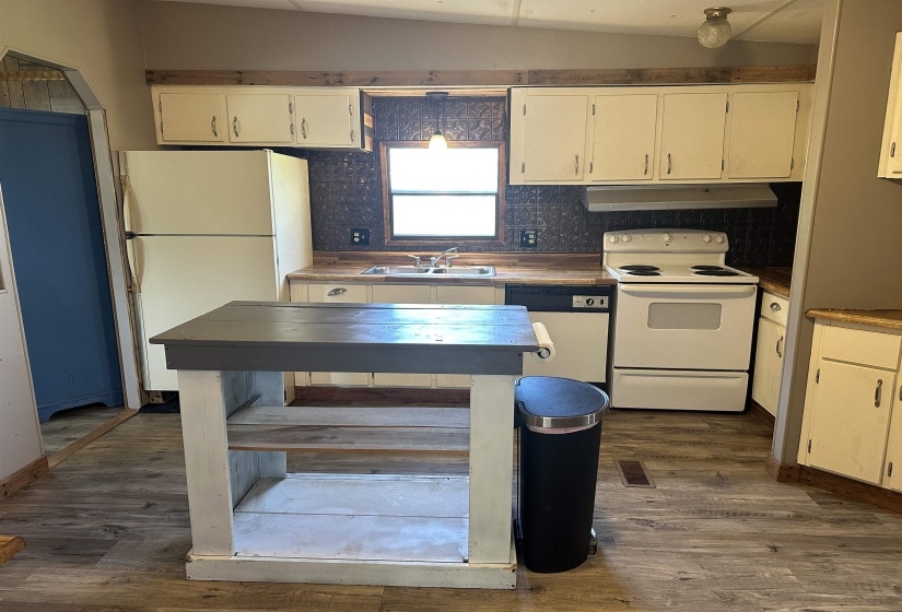 Kitchen with white appliances, backsplash, dark wood-type flooring, and white cabinets