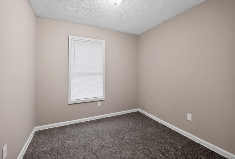 Unfurnished room with dark carpet and a textured ceiling