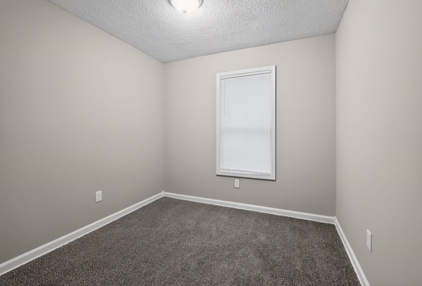 Unfurnished room with a textured ceiling and dark carpet