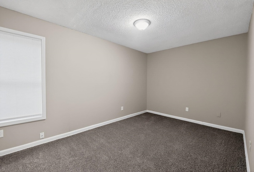 Unfurnished room with dark colored carpet and a textured ceiling
