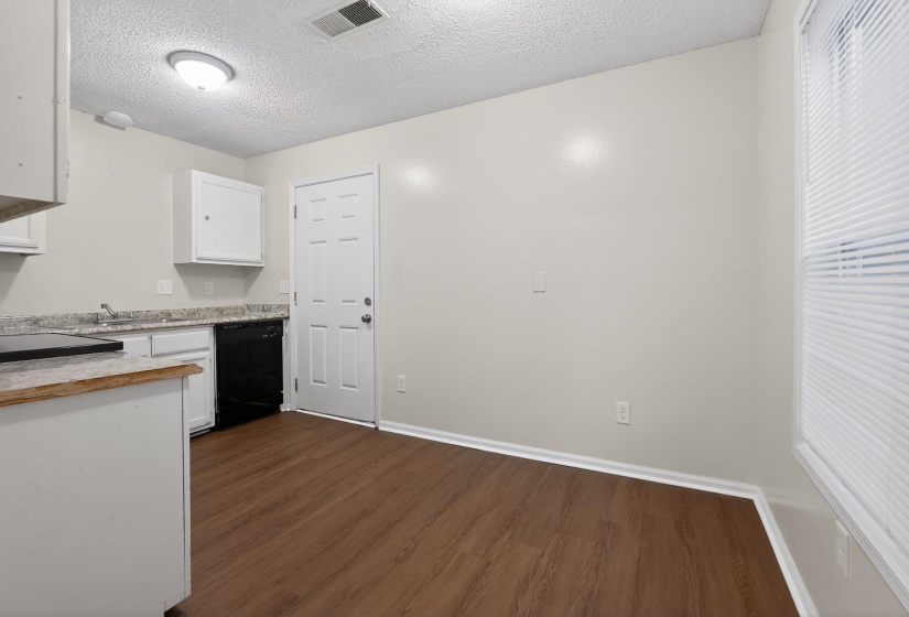 Kitchen with a textured ceiling, white cabinetry, dark wood-type flooring, and black dishwasher