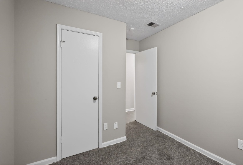 Unfurnished bedroom featuring a textured ceiling and dark carpet