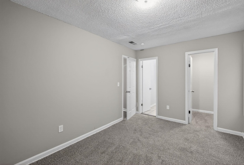 Unfurnished bedroom featuring a walk in closet, a textured ceiling, and carpet floors