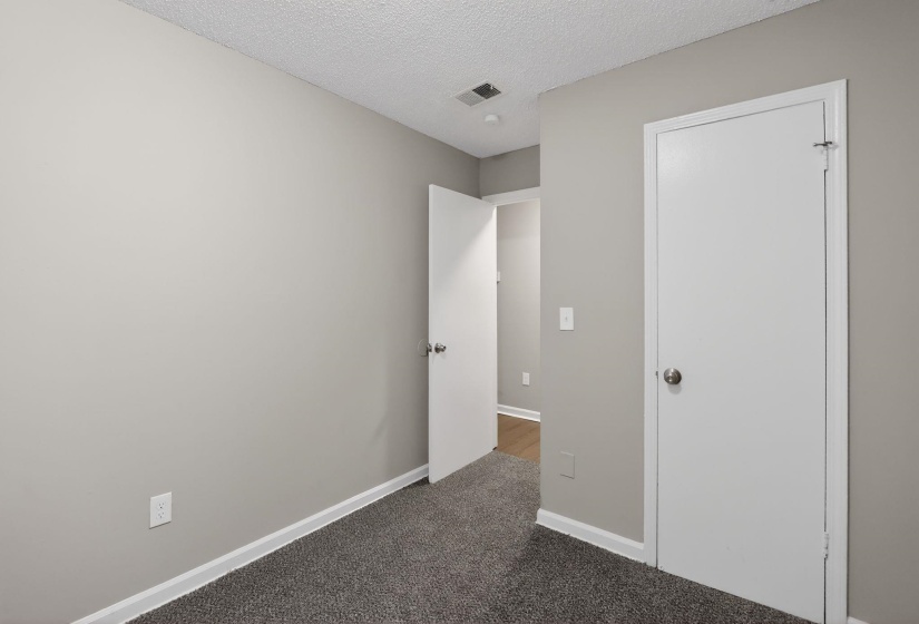 Unfurnished bedroom with a textured ceiling and light carpet