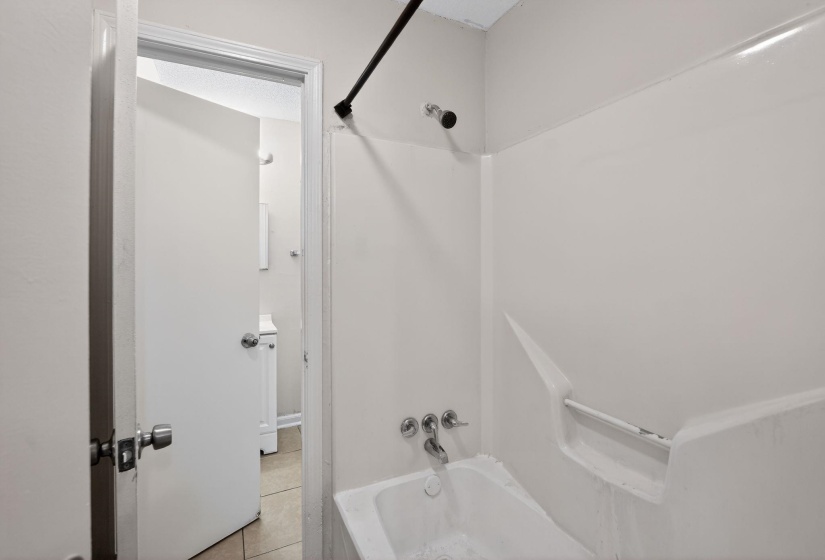 Bathroom featuring bathing tub / shower combination and light tile patterned flooring