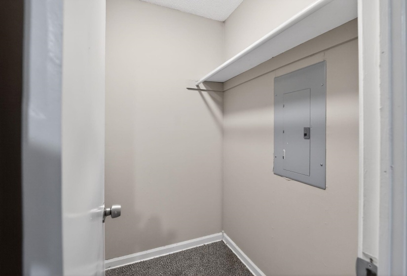Walk in closet with electric panel and dark colored carpet