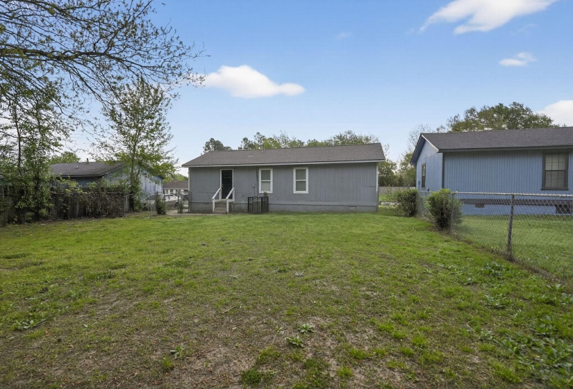 Back of property with a fenced backyard and crawl space