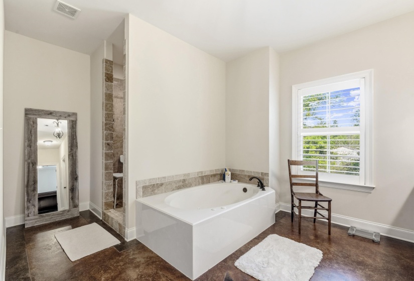Bathroom featuring a tile shower, a bath, and finished concrete flooring