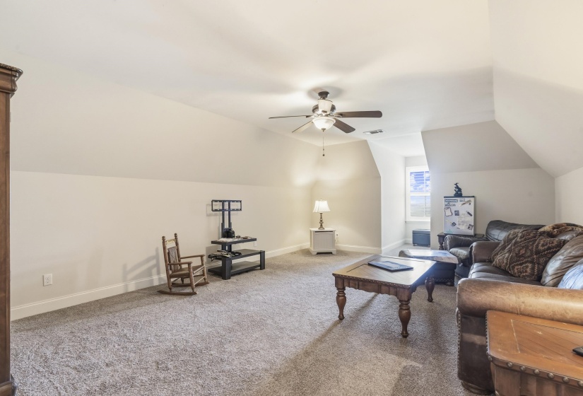 Carpeted living room with lofted ceiling and a ceiling fan