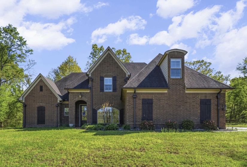 View of front of home featuring brick siding, a front yard, and a shingled roof