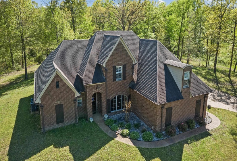 View of front of house featuring a shingled roof, a front lawn, and brick siding