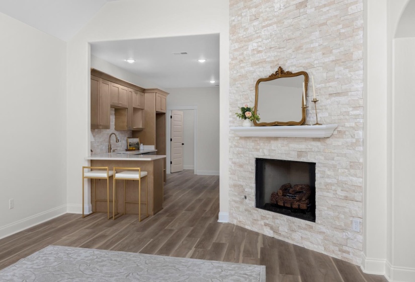 Stacked stone fireplace featuring a white mantel, an open firebox, and a hearth