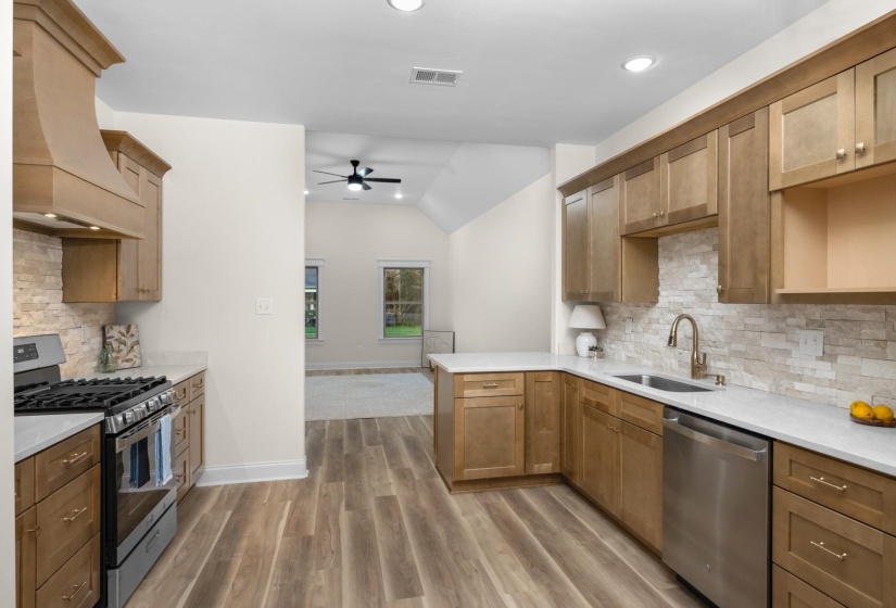 Kitchen featuring wood-finish flooring, light wood cabinetry, white countertops, and a stacked stone-look backsplash