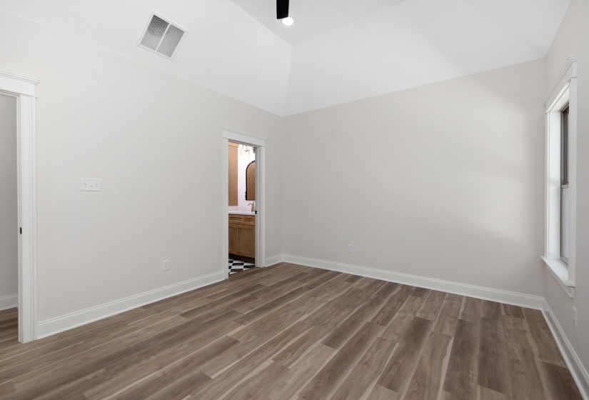 Unfurnished bedroom with vaulted ceiling, dark wood-style floors, a ceiling fan, and ensuite bath
