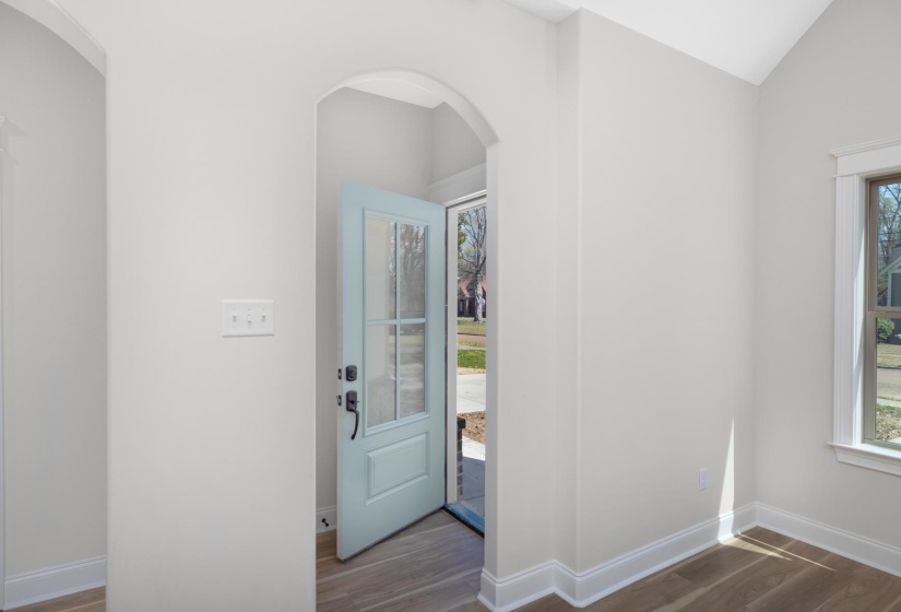 Entrance foyer featuring arched walkways, wood finished floors, and vaulted ceiling
