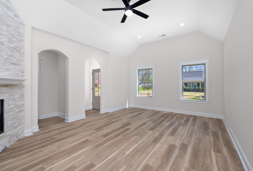 Unfurnished living room featuring ceiling fan, light wood-type flooring, recessed lighting, lofted ceiling, and arched walkways