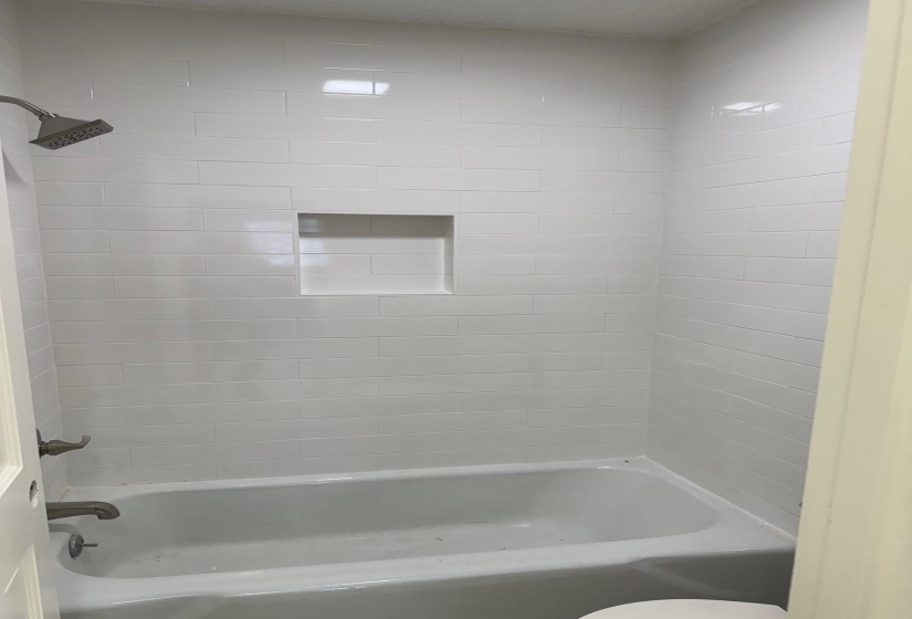 Bathroom featuring tiled shower / bath and toilet