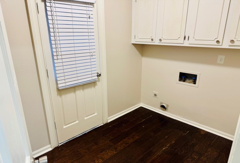 Laundry area with hookup for a washing machine, electric dryer hookup, dark hardwood / wood-style floors, and cabinets