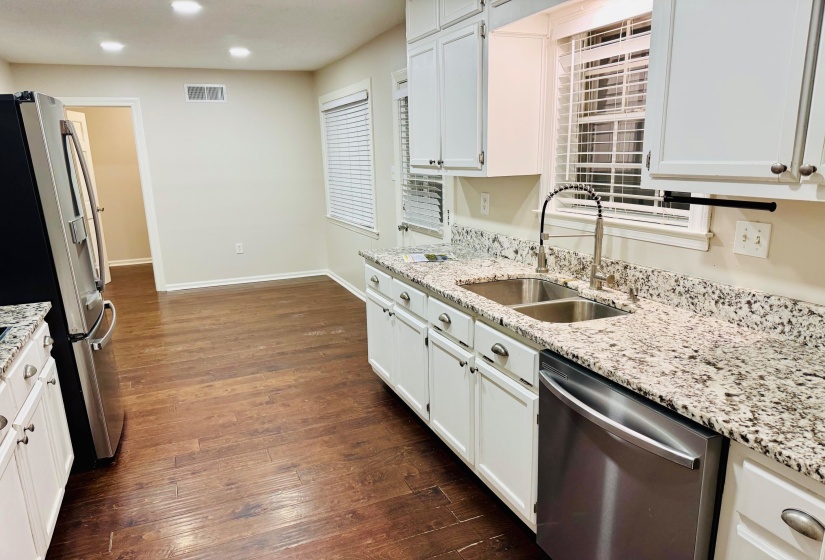 Kitchen with white cabinetry, appliances with stainless steel finishes, sink, and light stone counters