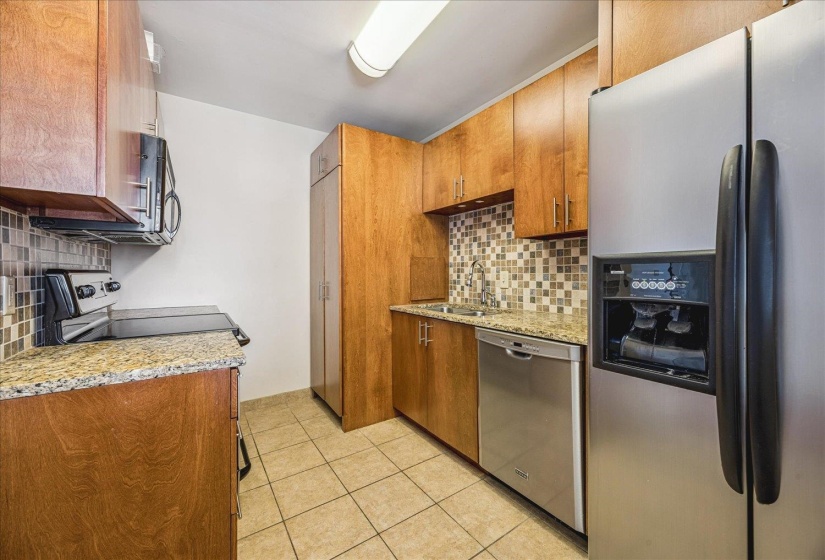 Kitchen featuring stainless steel appliances, light stone counters, wood finish cabinets, and backsplash